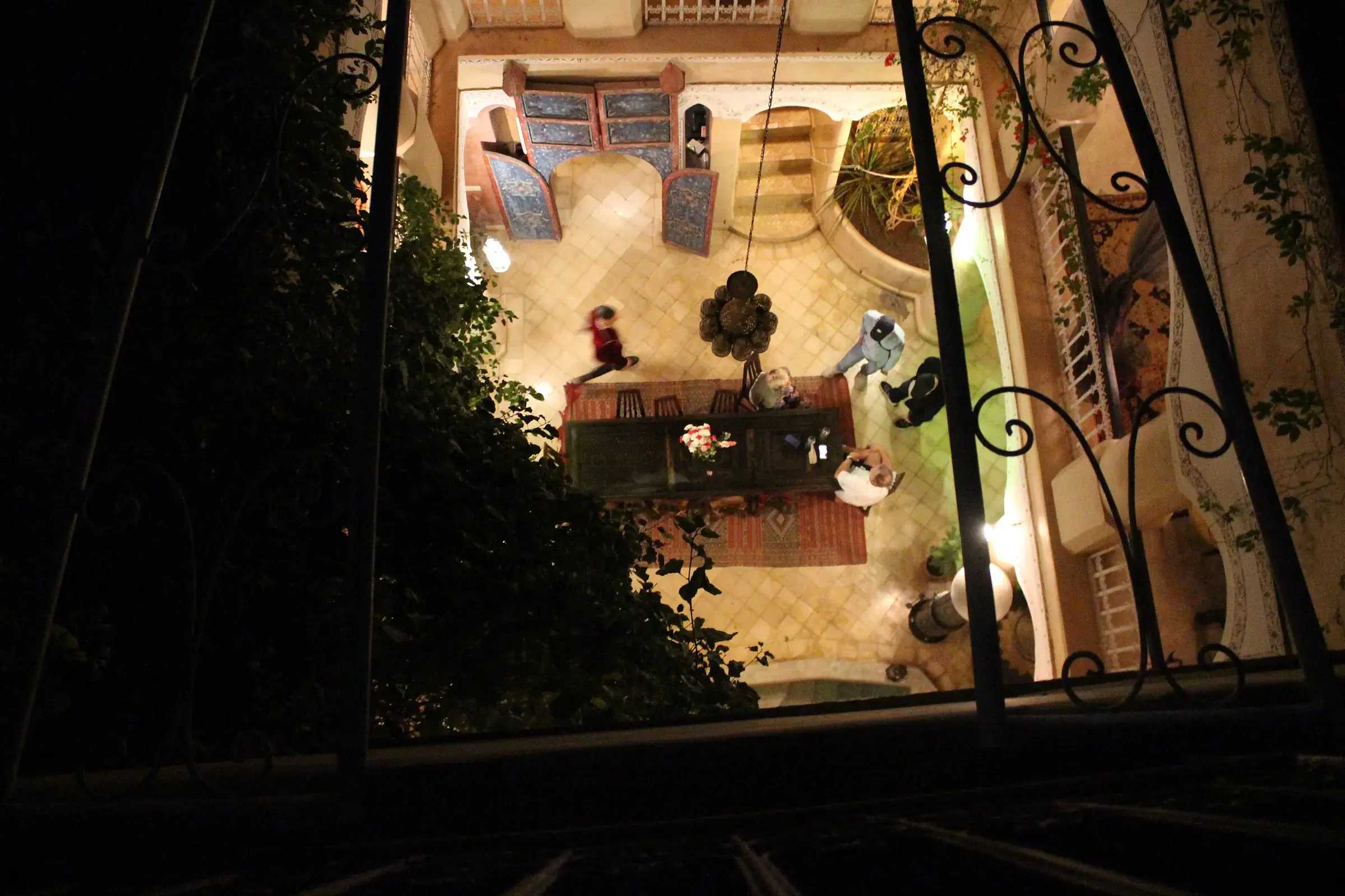 Courtyard of a medina riad seen from the roof at night, zellige tiles and lit lanterns